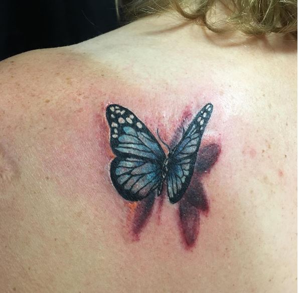 Realistic blue butterfly tattoo on left back shoulder