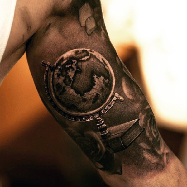 Realistic globe with book tattoo on upper arm