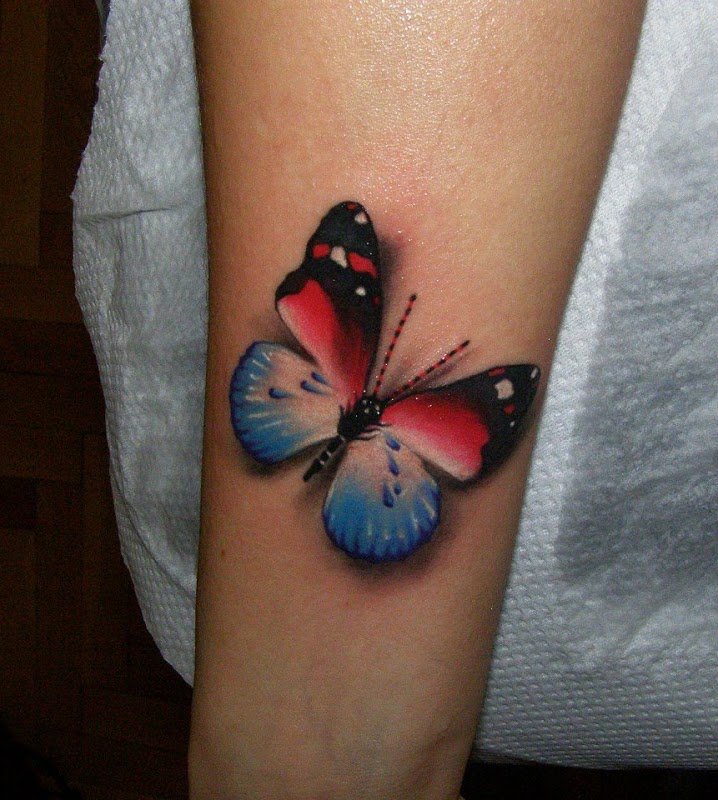 Red and blue butterfly tattoo on inner lower arm