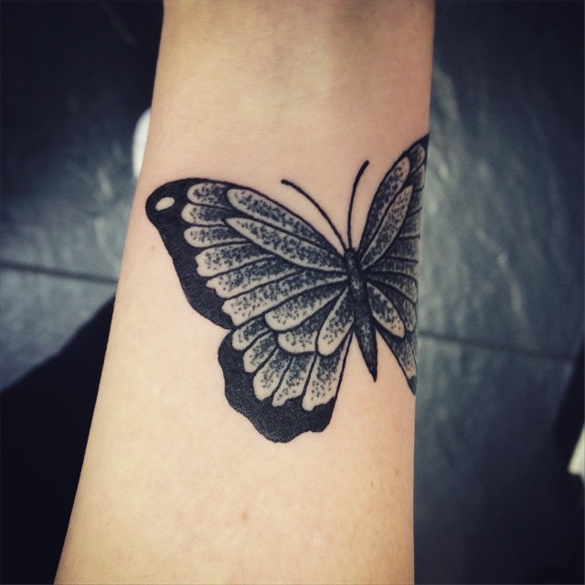 Simple black butterfly tattoo on inner arm
