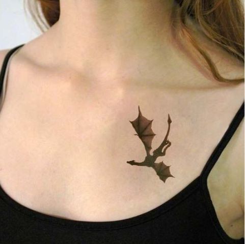 Tiny dragon tattoo on lower left neck of a woman