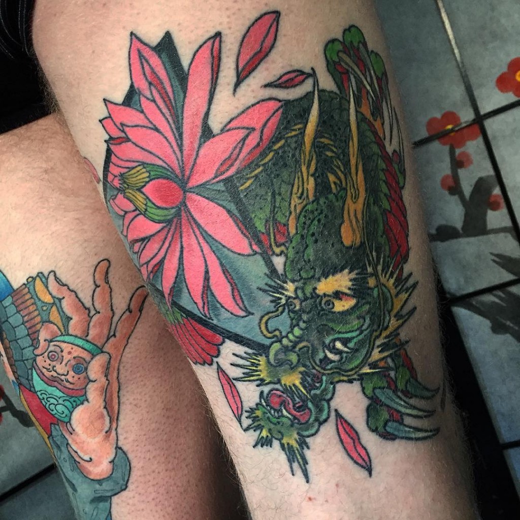 Traditional Green Color Dragon With Red Flowers Tattoo On Thigh