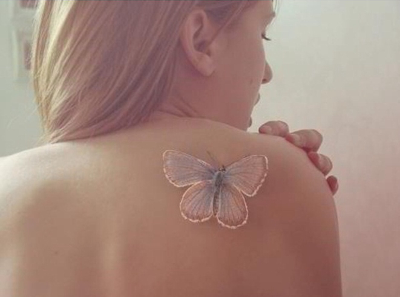 White butterfly tattoo on girl’s right shoulder.