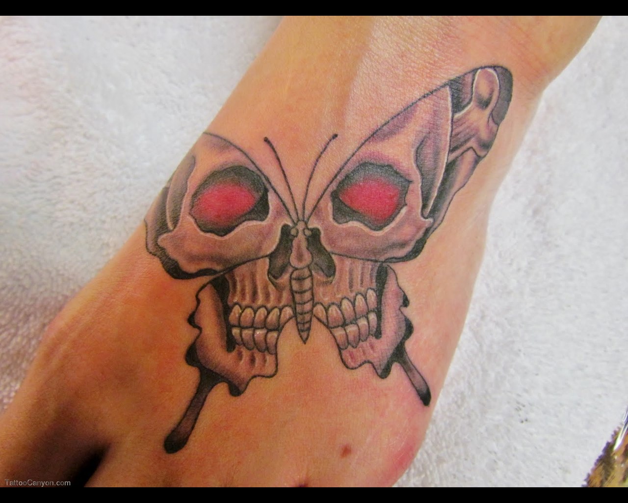 black skull butterfly tattoo on foot