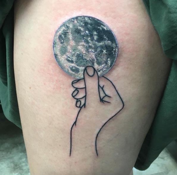Black and grey hand holding full moon tattoo on body