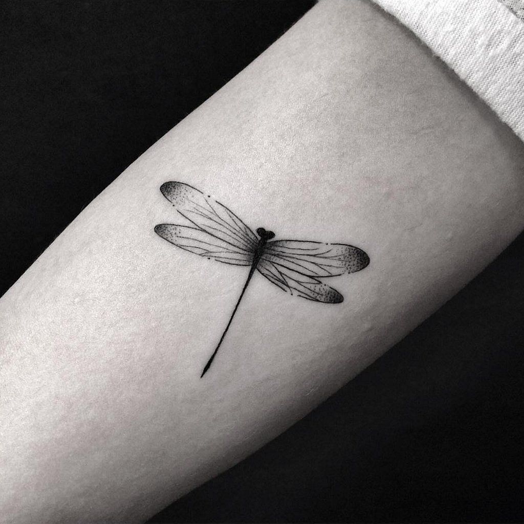 Black and white dragonfly tattoo on inner arm