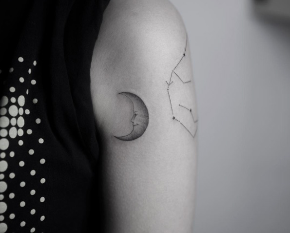 Black and white shaded evil moon tattoo on left upper arm