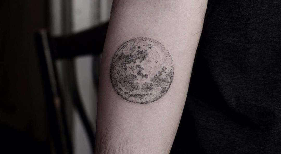 Black dotted full moon tattoo on inner arm