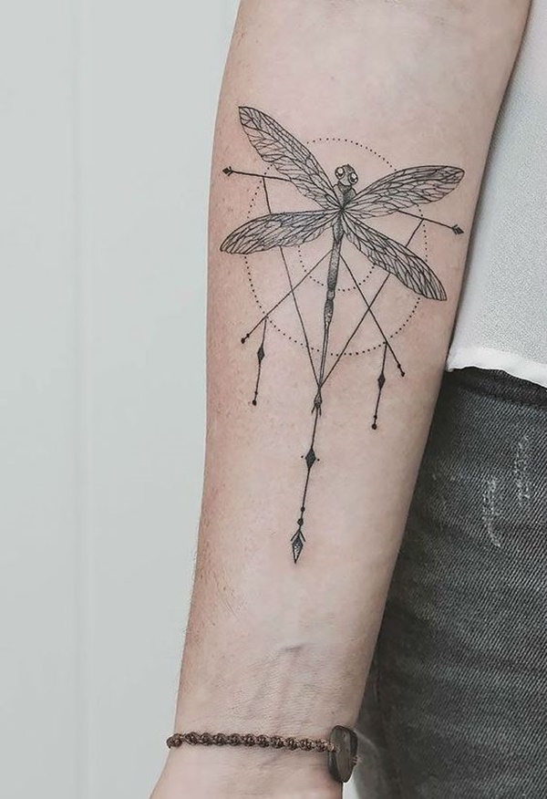 Black geometric dragonfly tattoo on lower inner arm