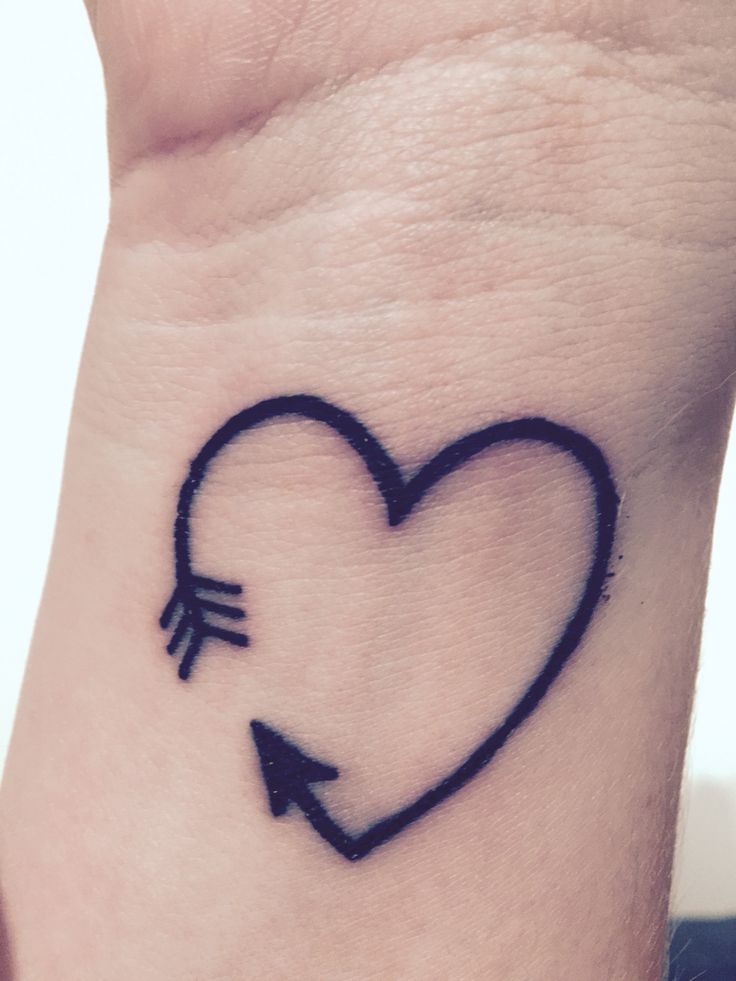 Black outlined arrow heart tattoo on left inner wrist