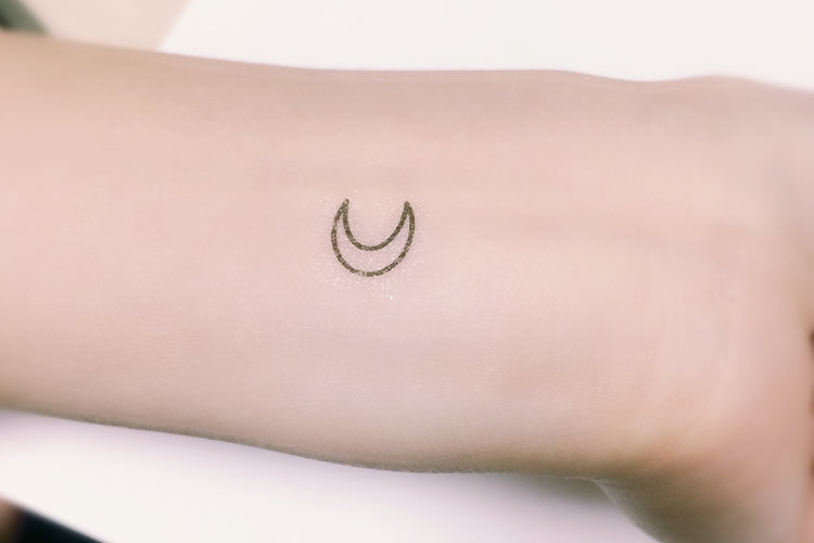 Black outlined tiny half moon tattoo on body