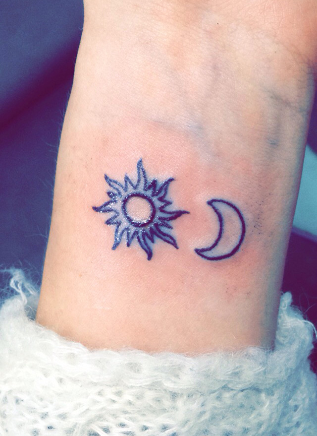 Black outlined tiny sun and half moon tattoo on inner wrist for women
