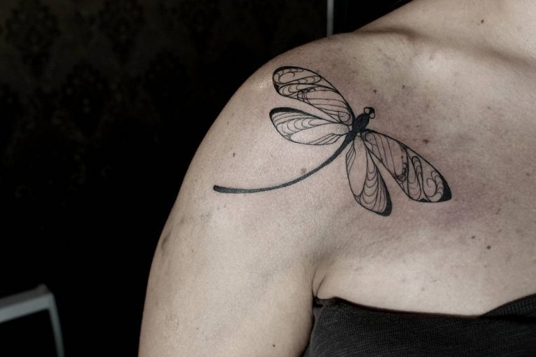 Black outlined tribal dragonfly tattoo on right front shoulder for women