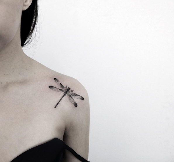 Black shaded dragonfly tattoo on front left shoulder for women