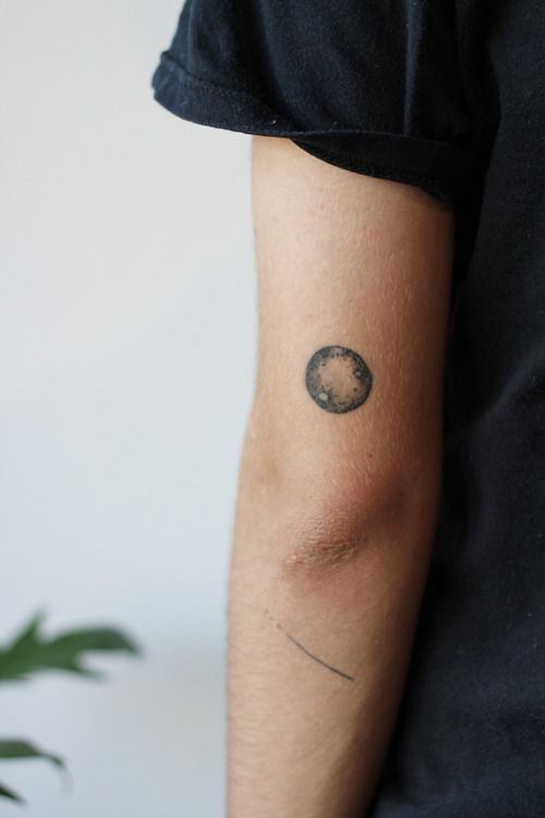 Black shaded tiny full moon tattoo above elbow