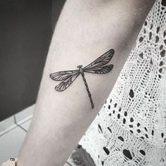 Black shaded tribal dragonfly tattoo on inner lower arm