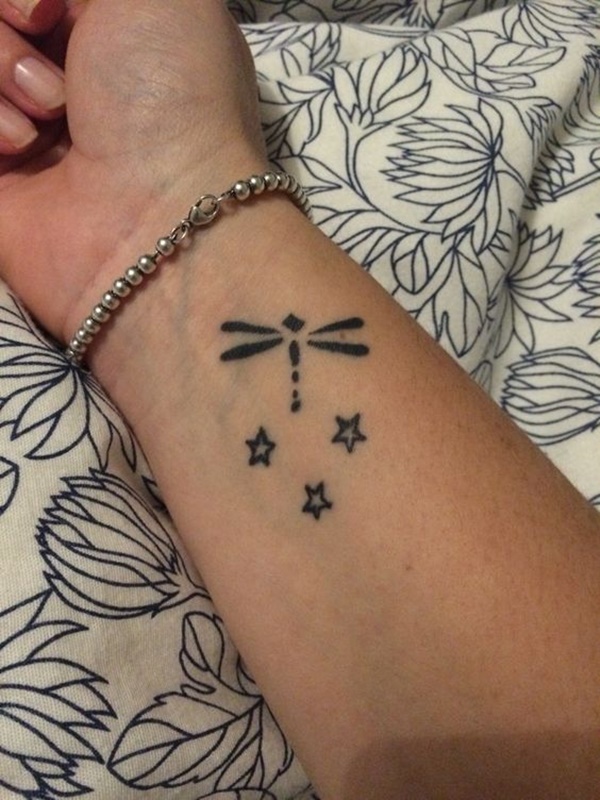 Black small dragonfly and stars tattoo on girl.s lower inner forearm