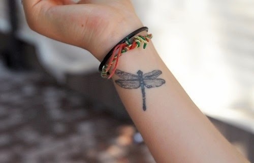 Black tribal dragonfly tattoo on inner lower arm