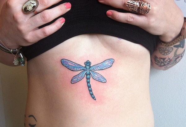 Blue colored dragonfly tattoo below girl’s breast