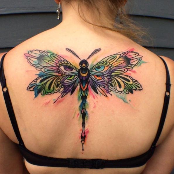 Colorful dragonfly wing eye tattoo on upper mid back for women