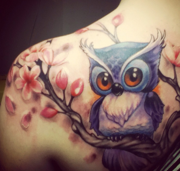 Cute blue baby owl with pink flowers tattoo on girl’s back shoulder