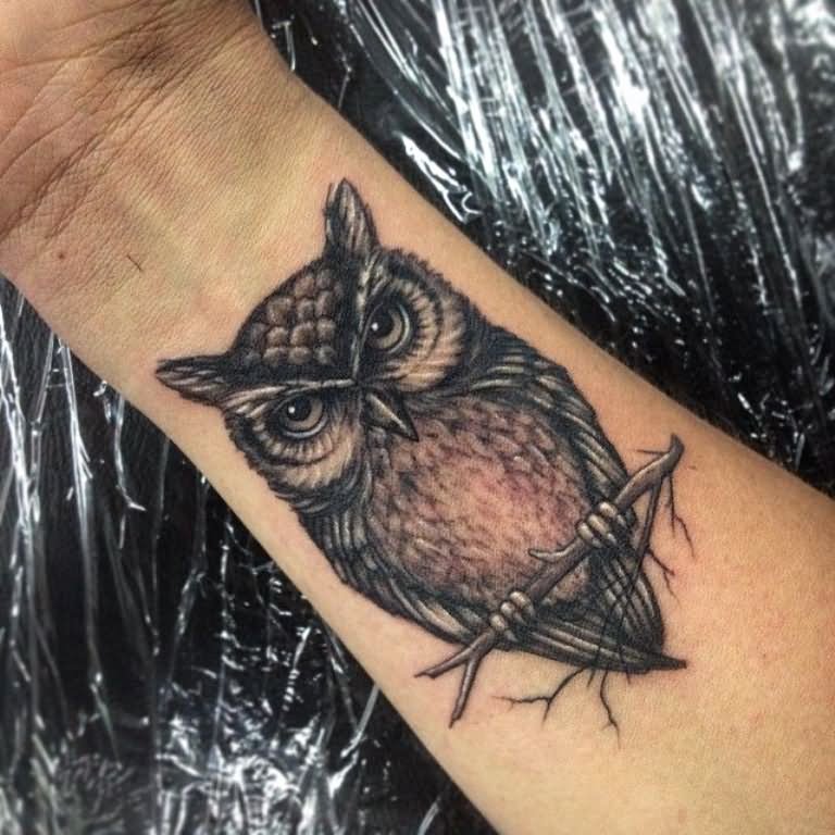 Grey realistic sitting owl tattoo on wrist