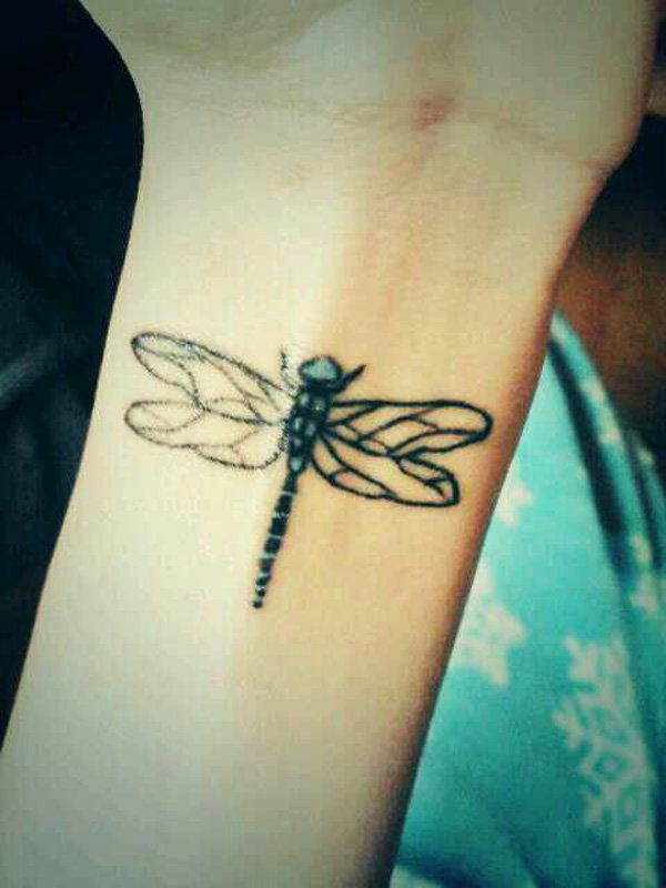 Green and black dragonfly tattoo on girl wrist