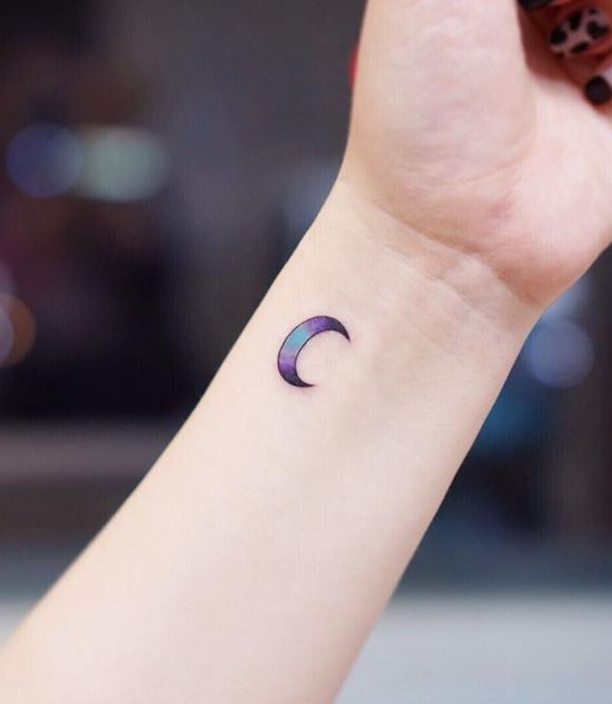 Purple and blue tiny moon tattoo on left wrist for women