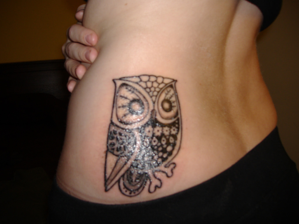 Small black ink baby owl tattoo on girl back waist