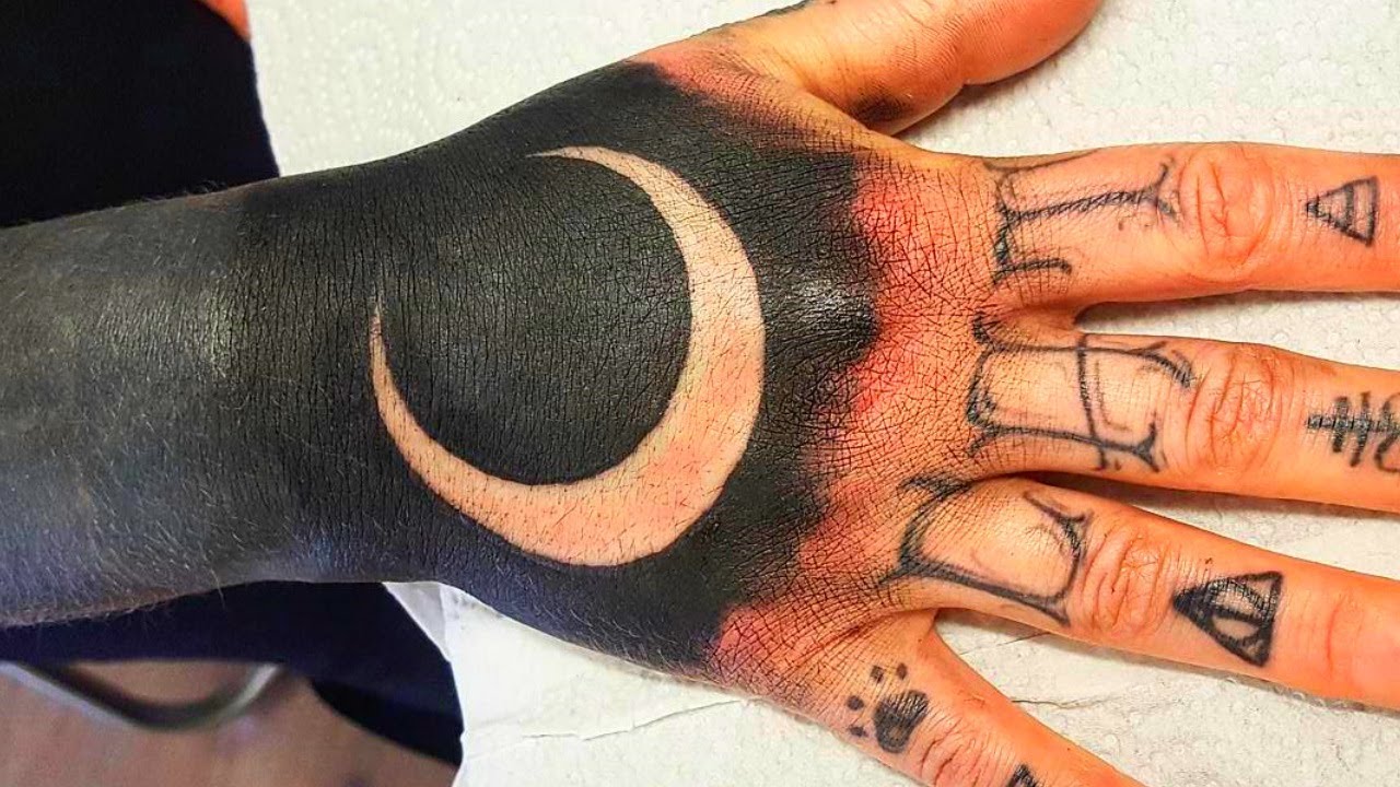 White and black half moon tattoo on upper hand for men