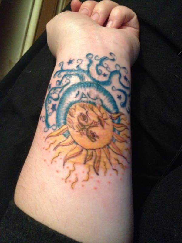 Yellow and blue ha;f sun and moon tattoo on lower inner arm