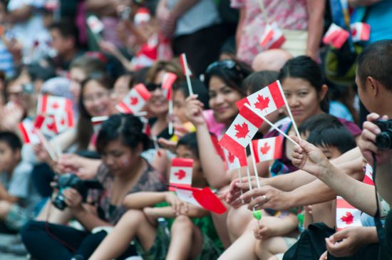 people waving canadian flags during Canada day parade