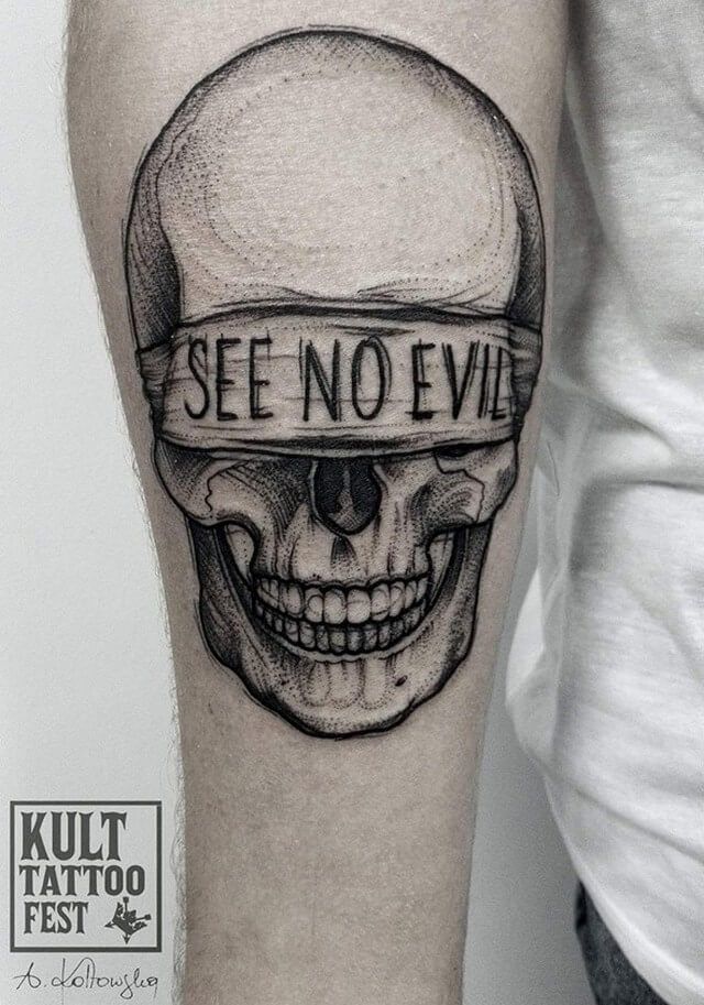 Black and grey shaded skull tattoo on inner arm