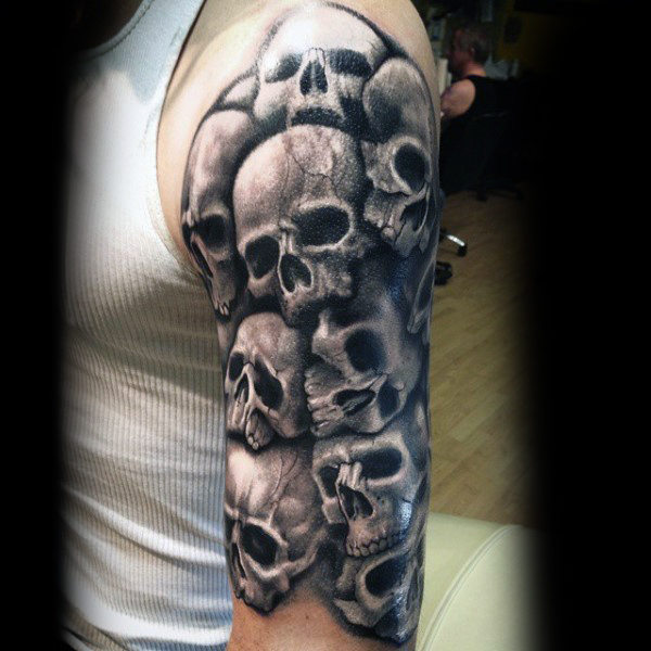 Black and grey shaded skulls tattoo on upper arm from men