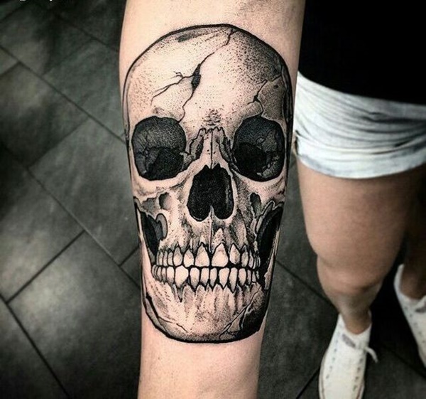 Black and grey skull tattoo on inner mid arm