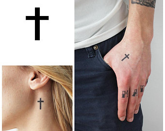 Black bold cross tattoos on upper hand and below ear