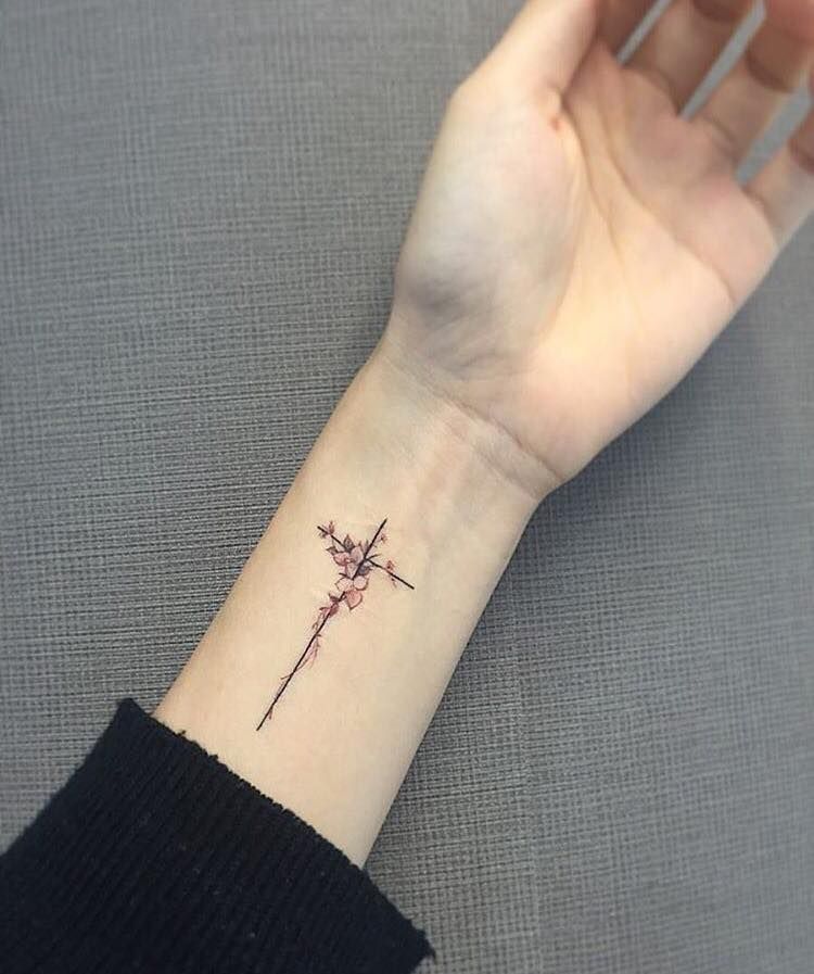 Black floral cross tattoo on inner lower arm for women