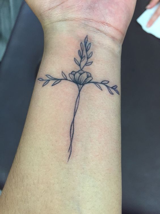 Black shaded flower cross tattoo on inner women inner forearm
