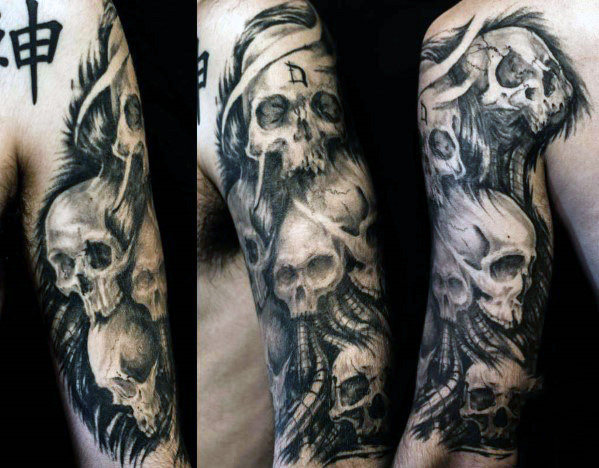 Black shaded multiple skulls tattoo on upper arm for men