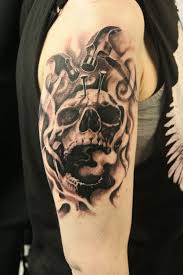Black shaded skull with hammer and nail tattoo on upper arm