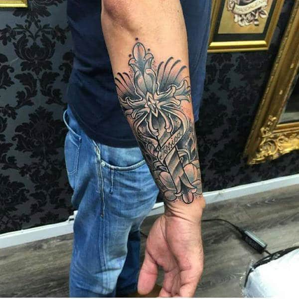 Blue and black cross tattoo design on forearm for men