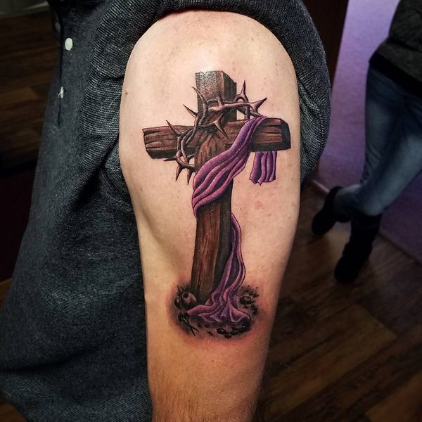 Brown wooden cross tattoo with barbed wire crown on left leg