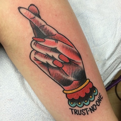 Colored fingers crossed trust no one tattoo on lower arm for women