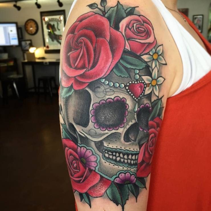 Colored skull with flowers tattoo on upper half arm for women