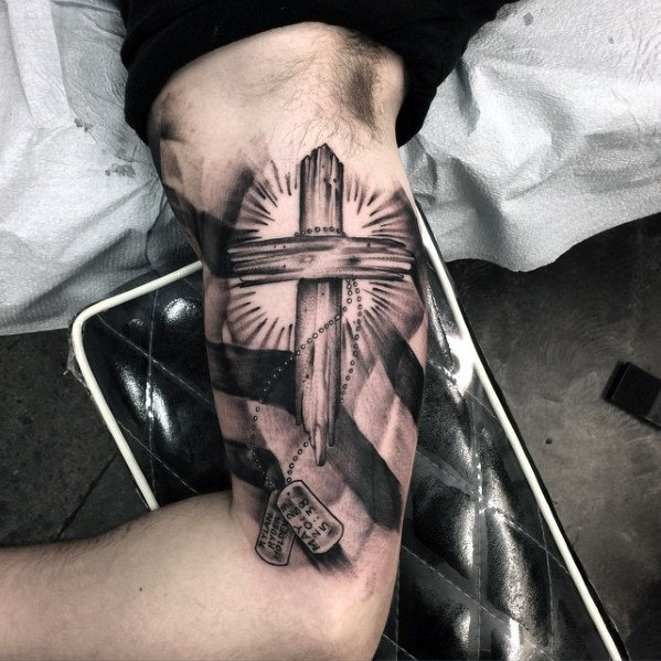 Grey shaded cross tattoo on upper arm for men