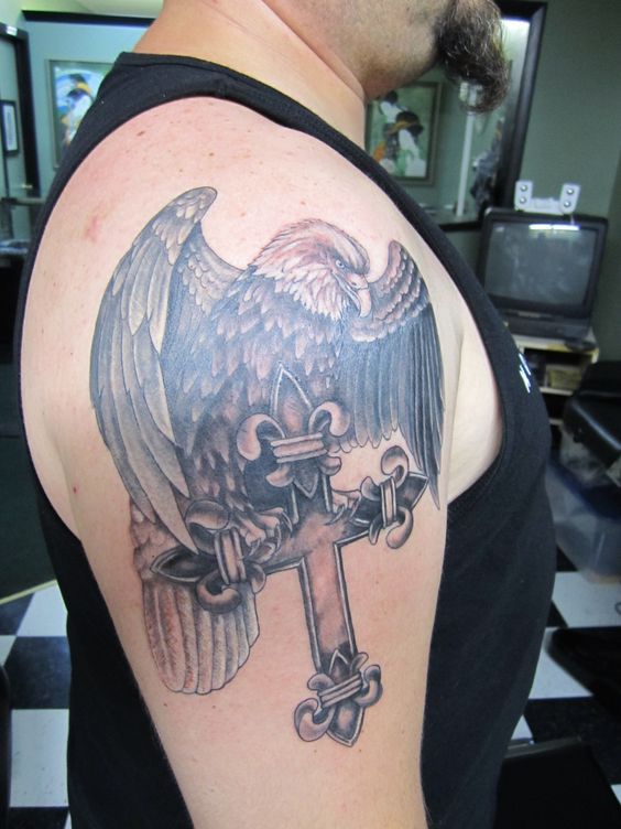 Grey shaded eagle with cross tattoo on upper right back