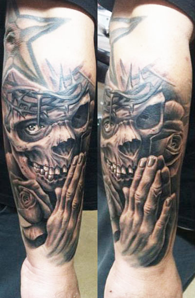 Grey shaded laughing skull with hand tattoo on arm by Josh Duffy