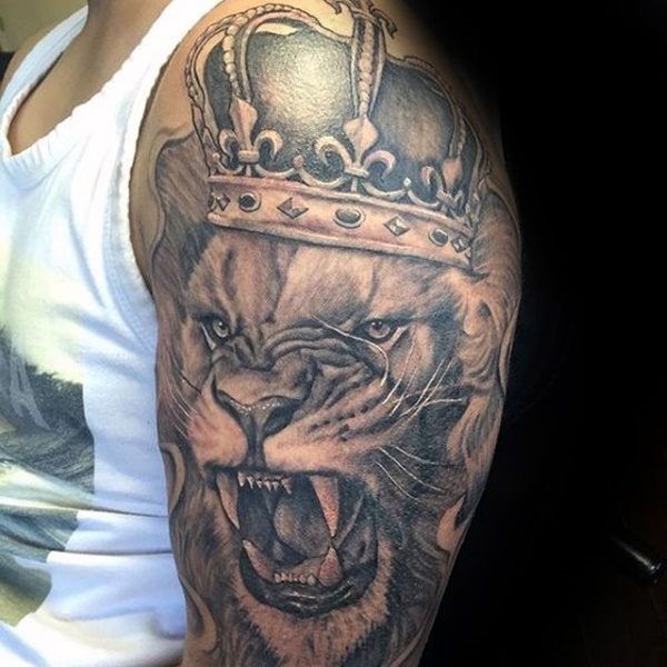 Grey shaded lion with crown tattoo on left upper sleeve