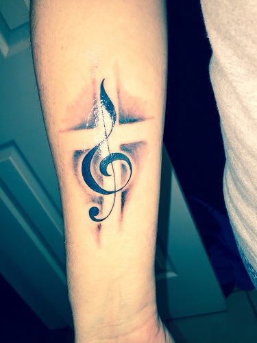 Grey shaded music note with cross tattoo on inner arm