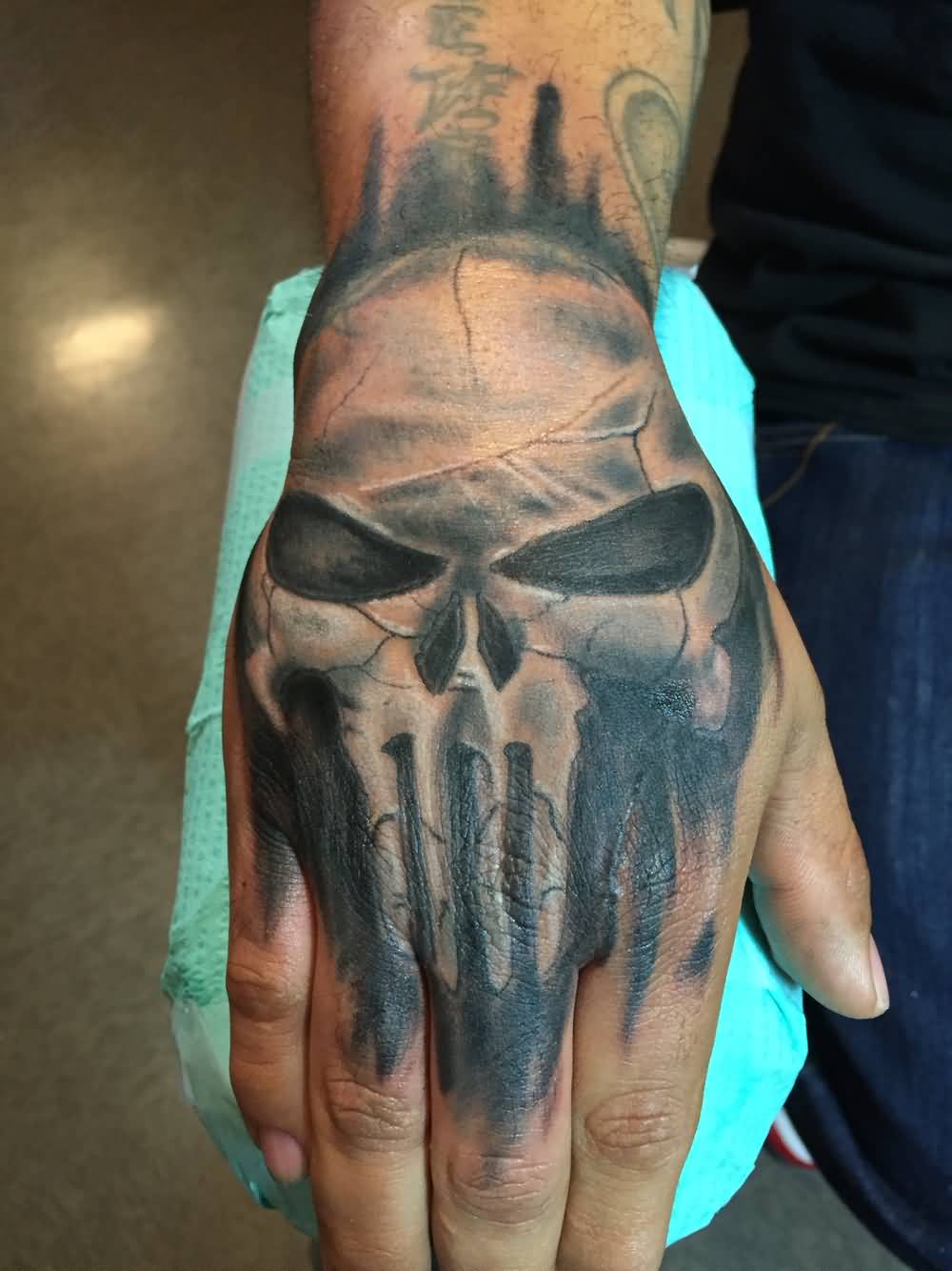 Black and grey shaded punisher tattoo on right fist